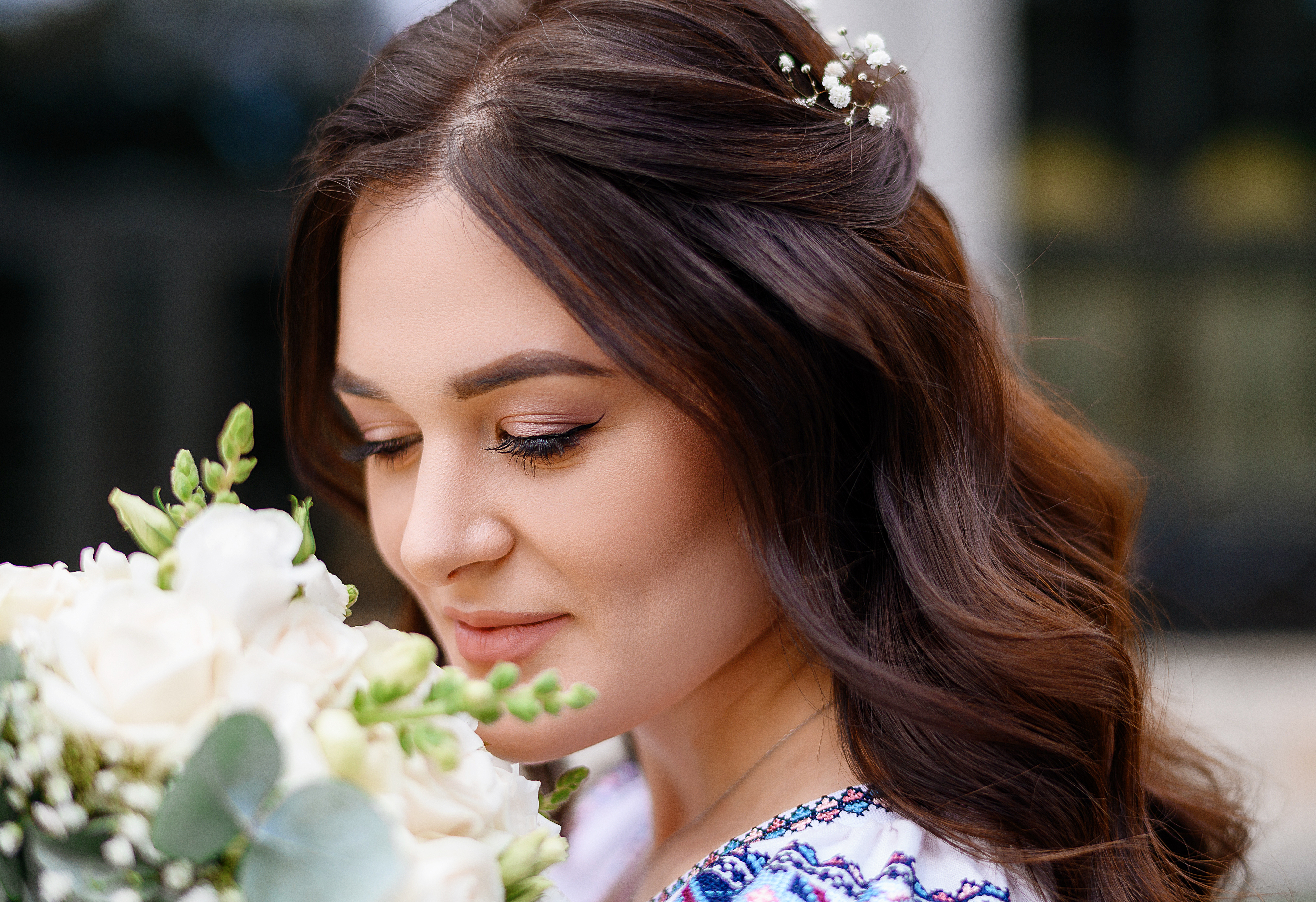 close view lovely face young girl which have brunette curly hair cute makeup holding bridal flowers looking down while smelling it