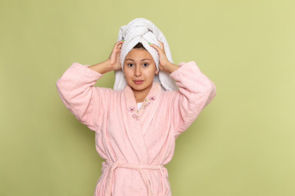 female pink bathrobe posing holding her head towel
