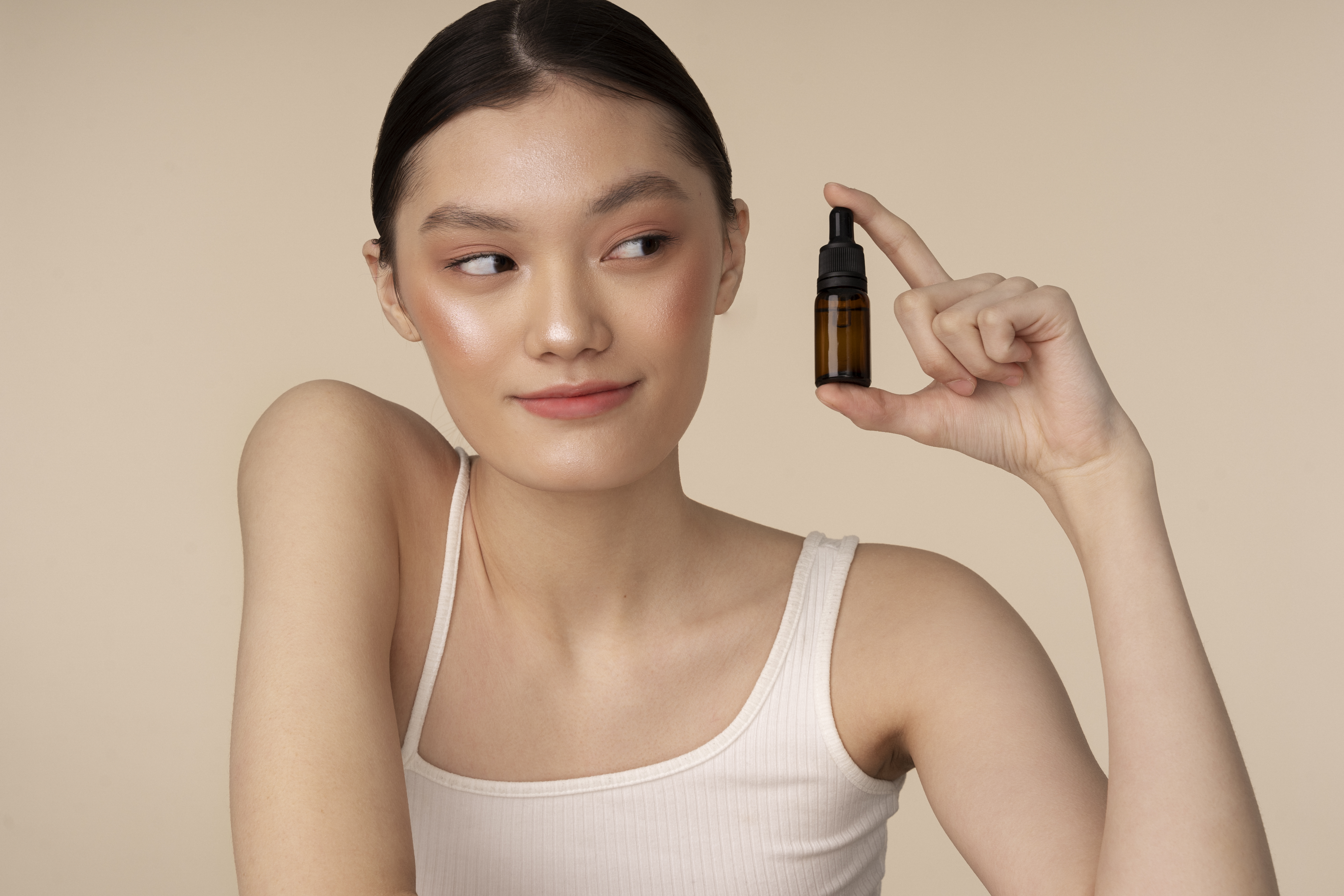 medium shot korean woman posing with serum bottle