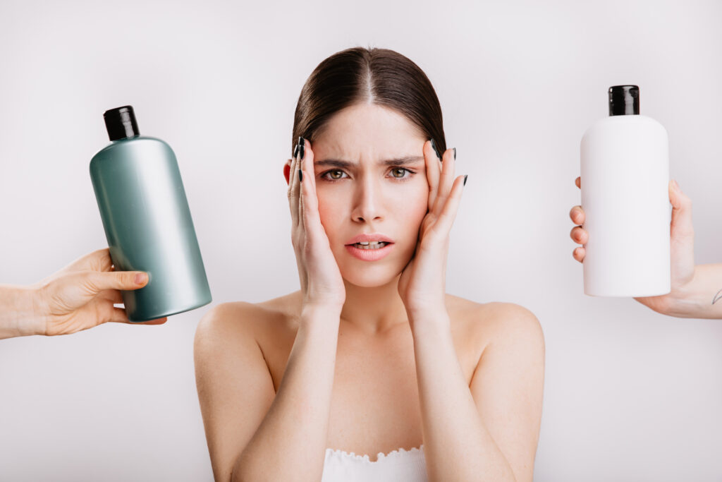 portrait of green eyed woman without makeup on isolated background. girl decides which shampoo is better to use.