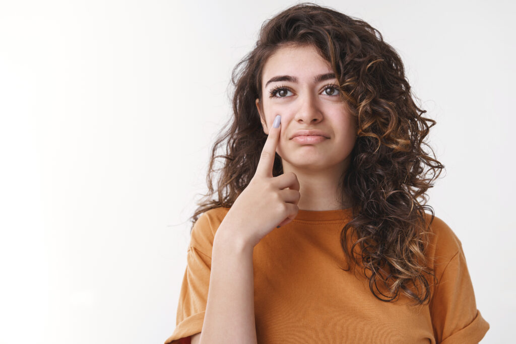 sarcastic cute curly haired armenian girl hold index finger camera like showing teardrop acting upset feel regret sadness standing bothered bad thoughts, whining complaining unlucky life