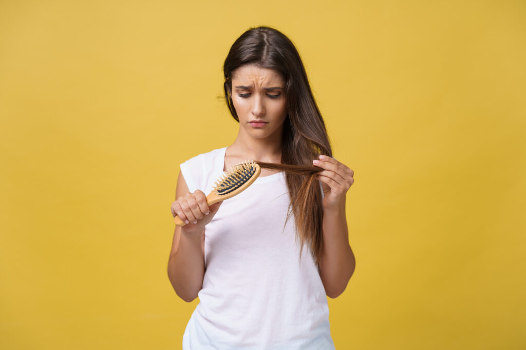 woman hand holding her long hair with looking at damaged splitting ends of hair care problems.