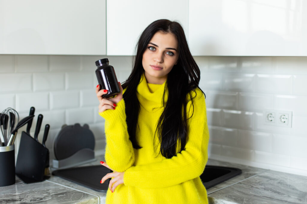 young woman eating pills and drinking water at home